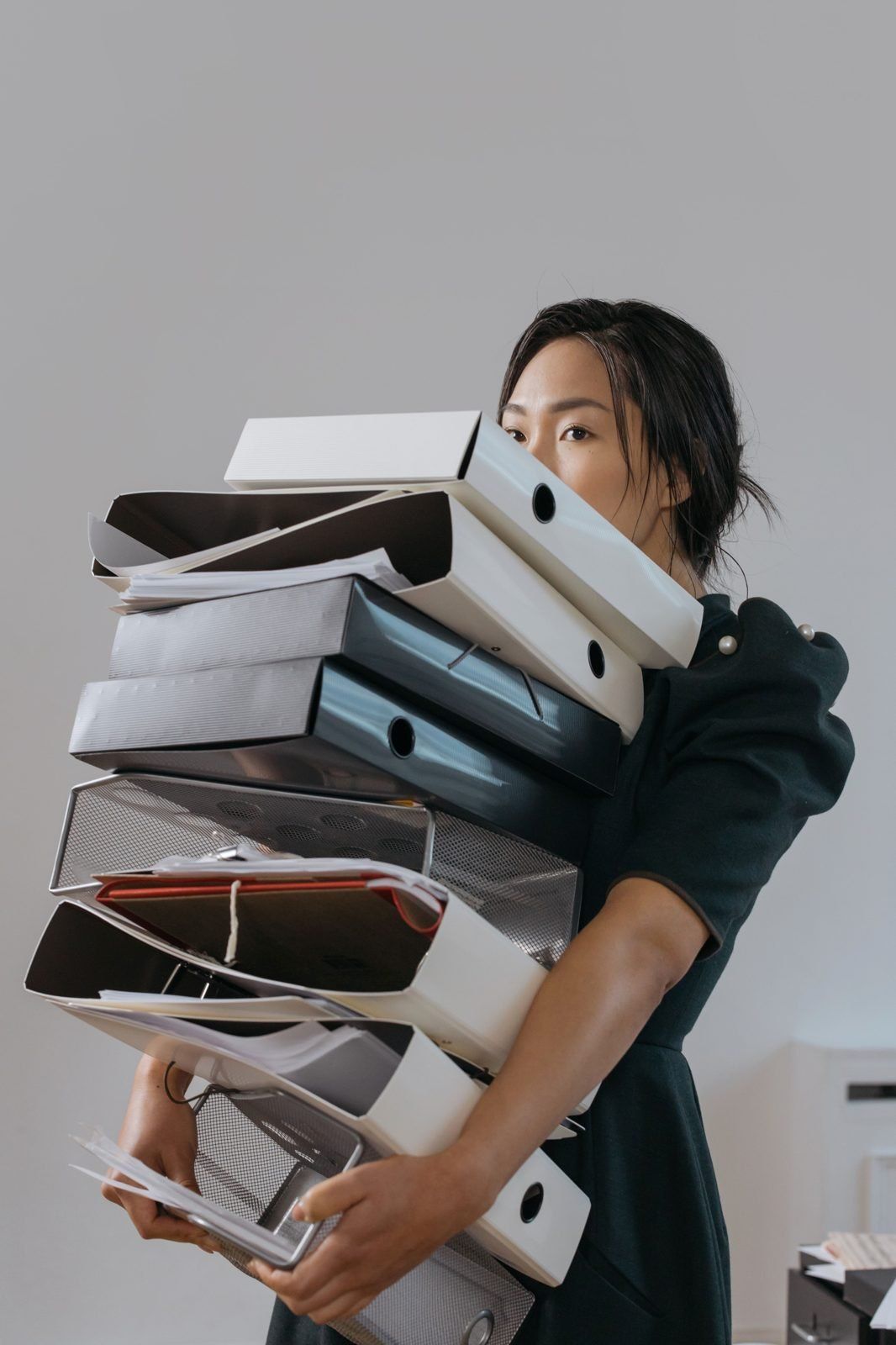 Woman carrying a tall stack of binders and files